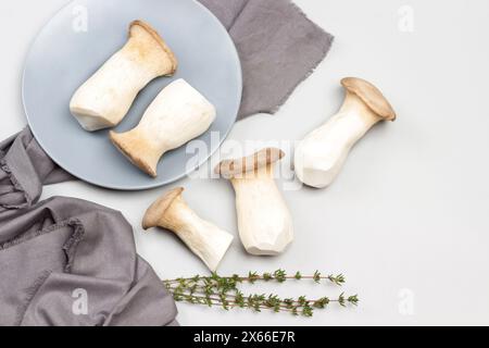 King Austernpilze auf grauer Keramikplatte und auf dem Tisch. Graue Serviette. Grauer Hintergrund. Flache Lagen Stockfoto