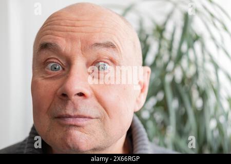 65-jähriger exzentrischer Mann, Senior mit Grimaces, Zwinkern, schelmischem Grinsen, der die Absurditäten des Lebens annimmt, komisch, komisch, ohne Angst, er zu sein und b Stockfoto