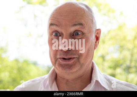 Mit verrücktem Glanz in den Augen, fröhlicher Seniorenmann mit Augenzwinkern, der die einfachen Freuden des Lebens annimmt, die einfachen Dinge im Leben genießt Stockfoto