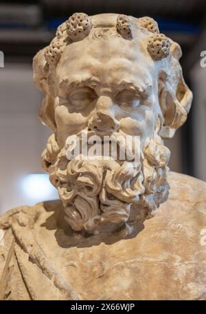 Nahaufnahme des Gesichts der antiken römischen Marmorstatue eines älteren Mannes mit Blumen auf dem Kopf Stockfoto