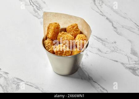 Goldene Hühnchennuggets in Edelstahleimer auf Marmoroberfläche Stockfoto