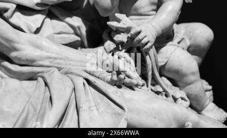 Schwarzweiß-Foto mit detaillierten Steinskulpturen, die einen Haufen geknickter Nägel darstellen, die von einer Kinderhand neben dem Leichnam Jesu gehalten werden Stockfoto