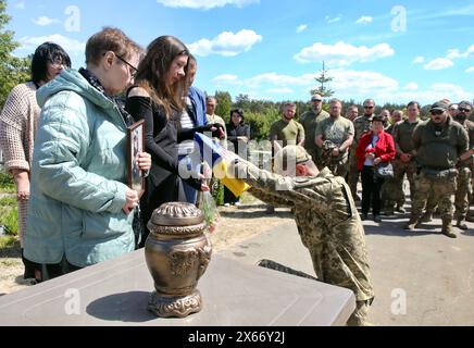 Nicht exklusiv: REGION KIEW, UKRAINE - 10. MAI 2024 - Ein Soldat überreicht den Angehörigen des Soldaten Jewhen Slyvka die Nationalflagge der Ukraine Stockfoto