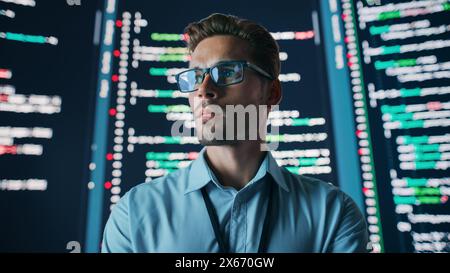 Innovatives Startup: Porträt eines durchdachten Softwareentwicklers, der eine Lösung findet, Datenanalyse mit großem Bildschirm durchführt. Programmierer, der E-Commerce-App entwickelt. Futuristische Dramatische Aufnahme Stockfoto