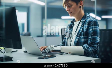 Vielfältiges Body positive Office: Porträt einer motivierten Frau mit Behinderung mit Hilfe einer Armprothese am Computer. Profi mit futuristischer, gedankengestützter myoelektrischer bionischer Hand Stockfoto