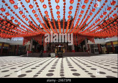 Lebendige Darstellung chinesischer roter Laternen bei einem Tempelfest. Eine große Menschenmenge versammelt sich tagsüber, um dieses traditionelle Ereignis zu feiern. Stockfoto