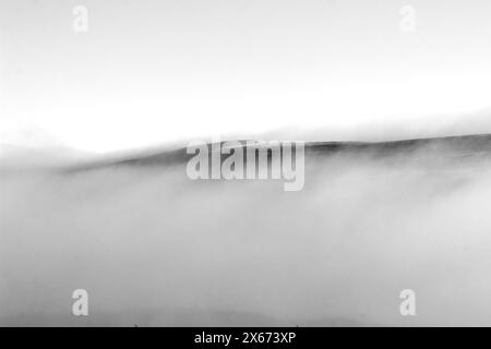 Mystischer Blick auf einen Bergkamm, der aus dem Morgennebel auftaucht. Fotografiert in den Drakensberg Mountains in Südafrika Stockfoto