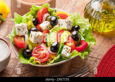 Griechischer Salat auf Holztisch, serviert und verzehrfertig. Stockfoto