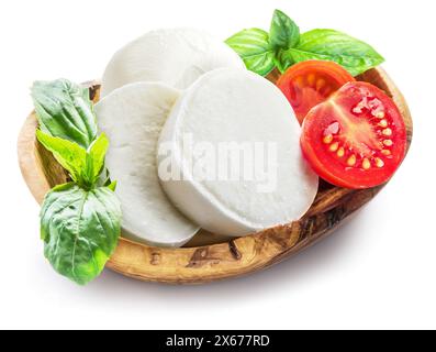 Büffelmozzarella mit Basilikumblättern und Tomaten in der Holzschale isoliert auf weißem Hintergrund. Traditionelle mediterrane Küche. Stockfoto