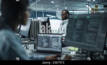 Diverse Multi-ethnische Teams im Büro: Indische weibliche und schwarze männliche IT-Programmierer, die am Desktop-Computer arbeiten. Spezialisten, Die Software Erstellen. Ingenieure Entwickeln App, Programm. Stockfoto