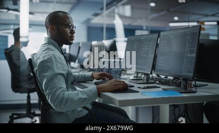 Authentic Office: Professioneller Black IT-Programmierer, der auf einem Desktop-Computer arbeitet. Männlicher Website-Entwickler und Software-Engineer entwickeln App, Videospiel. Terminal mit Programmiersprache Codierung Stockfoto