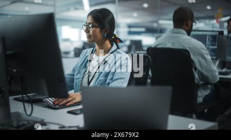 Diverse Büros: Porträt einer talentierten indischen IT-Programmiererin, die in einer freundlichen multiethnischen Umgebung am Desktop arbeitet. Software-Ingenieurin Mit Brillen Entwickelt Inspirierende App Stockfoto