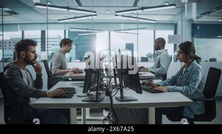 Vielfältiges Multi-ethnisches Team, das in Big City Office arbeitet: IT-Programmierer, die an Desktop-Computern arbeiten. Spezialisten, Die Innovative Software Entwickeln. Ingenieure Entwickeln Inspiration App, Programm. Stockfoto