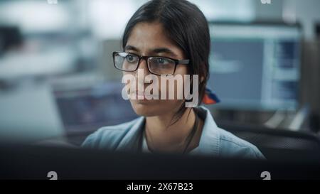 Diverse Büros: Porträt eines selbstbewussten indischen IT-Programmierers, der auf Desktop-Computern arbeitet. Spezialist Für Frauen, Die Brillen Tragen, Entwickeln Innovative Software. Professionelle Ingenieure Entwickeln Inspirierende App Stockfoto