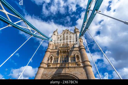 Blick von unten in Perspektive und Nadirebene auf Londons Tower Bridge, beleuchtet von der Sonne und mit den Schatten der Stahlseile an der Fassade Stockfoto