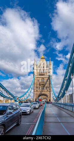 Autoverkehr und Touristen, die entlang der Tower Bridge in London spazieren, mit Blick auf die Spannstrukturen der Brücke an einem Tag mit sonnigem Wetter Stockfoto
