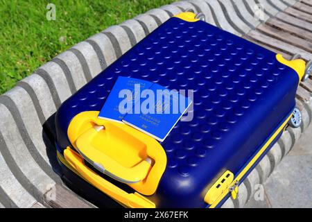 2 Pässe ukrainische Staatsbürger mit Inschrift auf Ukrainisch - Reisepass der Ukraine liegen auf gelb blauem Koffer in der Farbe der ukrainischen Flagge. Reisen, Zuflucht Stockfoto