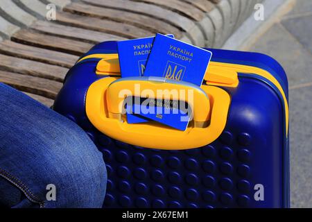 2 Pässe ukrainische Staatsbürger mit Inschrift auf Ukrainisch - Reisepass der Ukraine liegen auf gelb blauem Koffer in der Farbe der ukrainischen Flagge. Reisen, Zuflucht Stockfoto