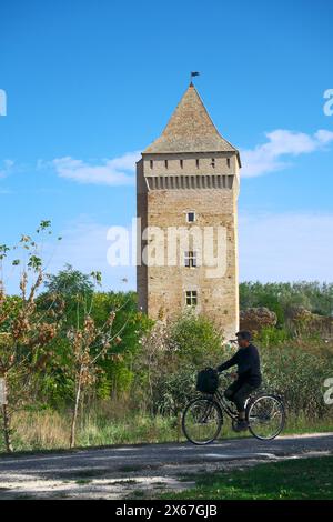 Verschwommene Silhouette einer älteren Frau auf dem Fahrrad auf dem Hintergrund ein befestigter Turm der Bac-Festung, Vojvodina, Serbien Stockfoto