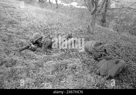 Wintermanöver, Reforger 1985, Zentralwächter, im Raum Kassel, Homberg/Efze, Neukirchen, Schwalmstadt, Vogelsberg, Frankenberg (Jan. - Feb. 1985), US-Soldat mit Maschinengewehr nimmt Position am Straßenrand ein, Schlafsäcke sind Teil der Ausrüstung Stockfoto