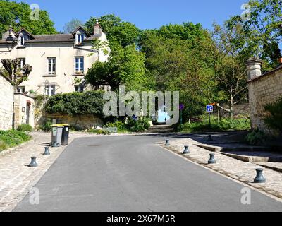 Straße und Pfad, der zu den Weizenfeldern führt, wo Van Gogh oft malte, mit einer Frau in Silhouette, Auvers-sur-Oise, Frankreich. Stockfoto