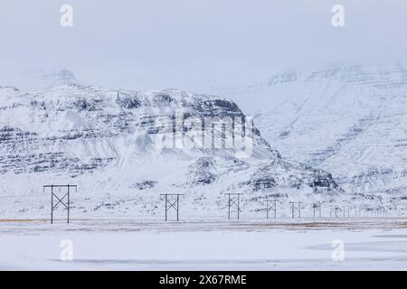 Typische isländische Winterlandschaft in den östlichen Fjorden mit Strommasten Stockfoto