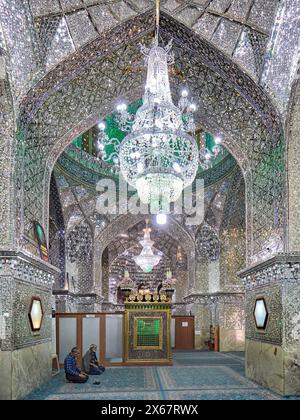 Männer beten im Ali Ibn Hamzeh Heiligtum, das im Inneren aufwendig mit glänzenden Spiegelfliesen (aina-kari) verziert ist. Shiraz, Iran. Stockfoto