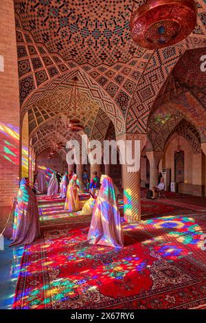 Touristen machen Fotos in der Nasir al-Mulk Moschee aus dem 19. Jahrhundert, auch bekannt als die Rosa Moschee, mit ihren mehrfarbigen Buntglasfenstern. Shiraz, Iran. Stockfoto