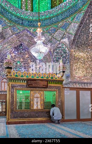 Ein Mann betet im Ali Ibn Hamzeh Heiligtum, das im Inneren aufwendig mit glänzenden Spiegelfliesen (aina-kari) verziert ist. Shiraz, Iran. Stockfoto