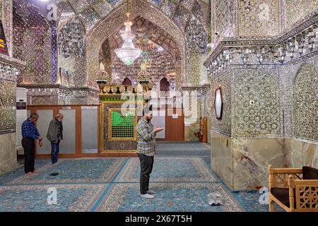 Männer beten im Ali Ibn Hamzeh Heiligtum, das im Inneren aufwendig mit glänzenden Spiegelfliesen (aina-kari) verziert ist. Shiraz, Iran. Stockfoto