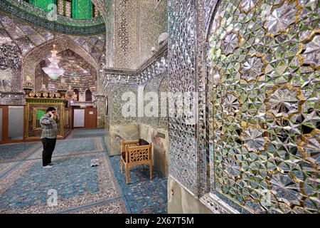 Ein Mann betet im Ali Ibn Hamzeh Heiligtum, das im Inneren aufwendig mit glänzenden Spiegelfliesen (aina-kari) verziert ist. Shiraz, Iran. Stockfoto