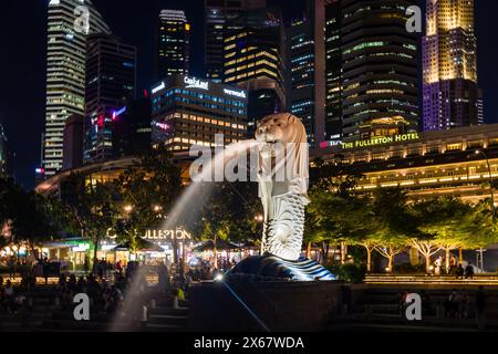 Menschenmassen rund um die Merlion Statue in der Marina Bay Gegend der Stadt Singapur bei Nacht Stockfoto
