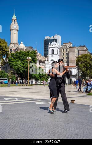 Buenos Aires, Argentinien, Tangotanz auf der Plaza de Mayo, ein junges Paar tanzt Tango für Touristen und einheimische Passanten und sammelt etwas Geld mit einem Hut, hinten der Cabildo de Buenos Aires, ein offizielles Gebäude, das während des Vizekönigs des R'o de la Plata als Regierungssitz diente, heute ist es ein Museum. Stockfoto