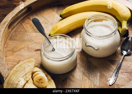 Zwei Gläser Bananenjoghurt auf einem Holztablett. Stockfoto