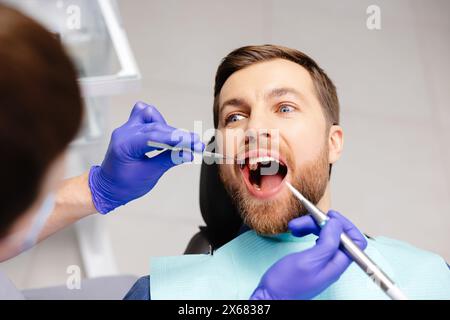 Ein Mann, der Zähne beim Zahnarzt untersuchen lässt. Ubersicht über die Kariesprophylaxe. Stockfoto