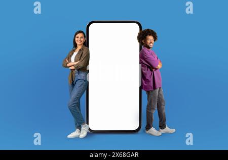 Zwei lächelnde Menschen, die sich auf ein riesiges Smartphone stützen Stockfoto