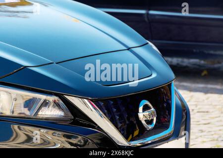 uschgorod, ukraine - 31. oktober 2021: nissan-Ornament auf dem Kühlergrill eines blauen Elektroautos. Nahaufnahme im Freien Stockfoto