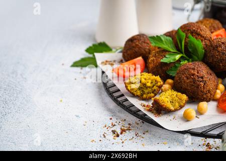 Stehen Sie mit köstlichen Falafelbällchen, Kichererbsen und Tomaten auf hellem Hintergrund, Nahaufnahme Stockfoto