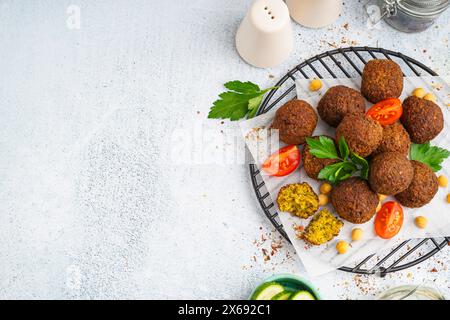 Stehen Sie mit köstlichen Falafelbällchen, Kichererbsen und Tomaten auf hellem Hintergrund Stockfoto