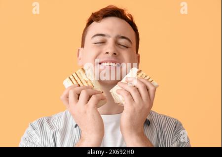 Junger glücklicher Mann lächelt und hält Döner auf beigefarbenem Hintergrund Stockfoto
