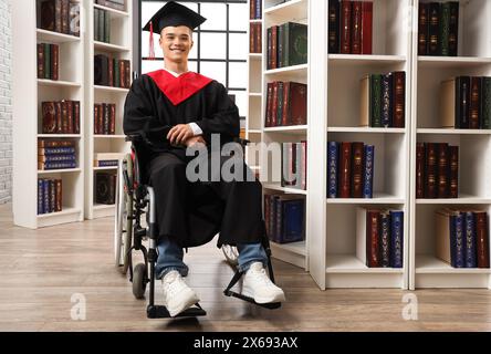 Männlicher Absolvent im Rollstuhl in der Bibliothek Stockfoto