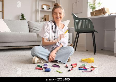 Junge Frau, die zu Hause mit verschiedenen elektronischen Einwegzigaretten auf dem Boden sitzt Stockfoto