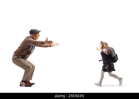 Profilaufnahme eines Schulmädchens mit einem Rucksack, der auf ihren Großvater zuläuft, isoliert auf weißem Hintergrund Stockfoto