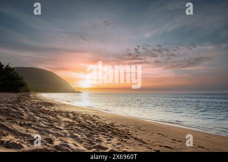 Guadeloupe, eine karibische Insel auf den französischen Antillen. Blick auf den Strand Grande Anse. Einsame Bucht, Füße im Sand und Blick auf das Meer bei Sonnenuntergang. Landschaftsaufnahme eines tropischen Traums, Wellen, Palmen Stockfoto