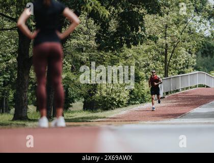 Aktive Männer und Frauen joggen auf einem malerischen Parkweg, umgeben von üppigem Grün Stockfoto