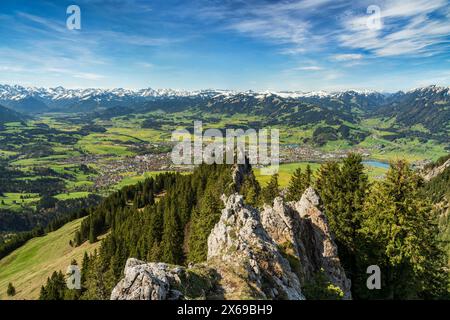 Frühling in den Bergen. Blick von den Grünten ins Illertal bei Sonthofen. Wiesen, Wälder und schneebedeckte Berge unter blauem Himmel. Allgäuer Alpen, Bayern, Deutschland, Europa Stockfoto