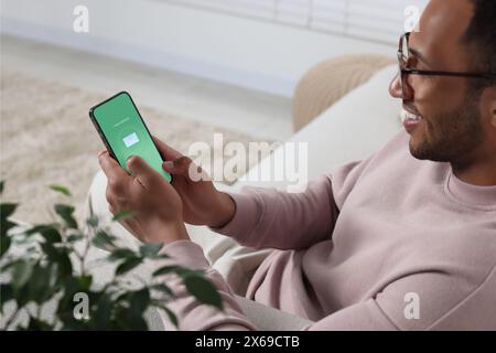 Mann überprüft neue Nachricht auf dem Handy drinnen Stockfoto