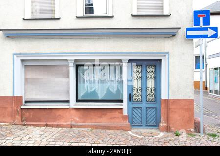 Alte blaue Tür mit Glasfenstern führt zu einem grauen Haus. Straße mit Häusern und singen in Deutschland. Stockfoto