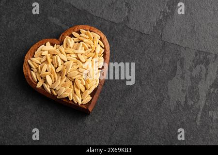 Risoni, Bio-Pasta in herzförmiger Schüssel - roh getrockneter Orzo Stockfoto