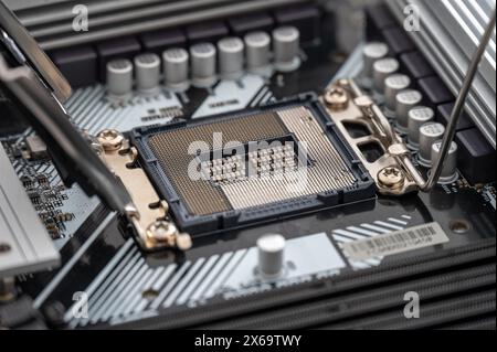 Hochauflösendes Bild eines offenen CPU-Sockels auf einem modernen Mainboard, das die komplizierte Anordnung der Stifte und die Komponenten in der Nähe beschreibt. Stockfoto